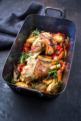Traditional braised leg of lamb with eggplant, potatoes and tomatoes offered as close-up in a rustic old roasting dish