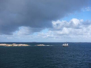 Sailing ship near some rocky islands on the ocean.