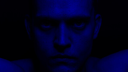 portrait of a young man in blue neon on a black background
