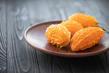 Momordica charantia on a wooden background. Ripe whole fruits of Momordica charantia, also known as bitter melon or bitter squash. Selective focus.