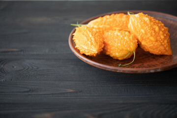 Momordica charantia on a wooden background. Ripe whole fruits of Momordica charantia, also known as bitter melon or bitter squash. Selective focus.