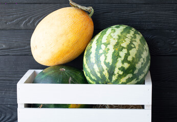 Large juicy watermelon and aromatic melon are waiting for cutting on the wooden table, summer freshness.