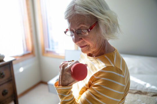 Senior woman exercising with dumbbell in bedroom