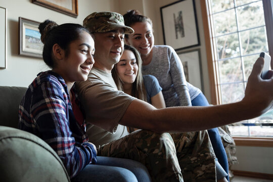 Happy military family taking selfie on sofa