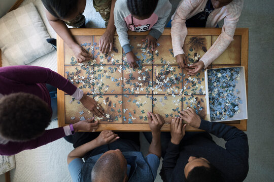 Overhead View Family Assembling Jigsaw Puzzle On Coffee Table