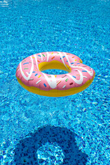 pink inflatable donut doughnut floating mattress in swimming pool. Beach pool accessories. Summer holiday concept