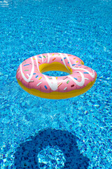 pink inflatable donut doughnut floating mattress in swimming pool. Beach pool accessories. Summer...