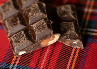 Broken chocolate pieces on wooden background. Selective focus.