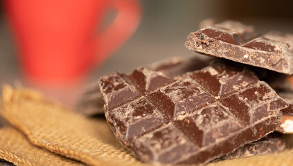 Broken chocolate pieces on wooden background. Selective focus.