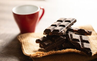 Broken chocolate pieces on wooden background. Selective focus.