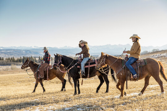 Ranchers horseback riding on sunny winter ranch
