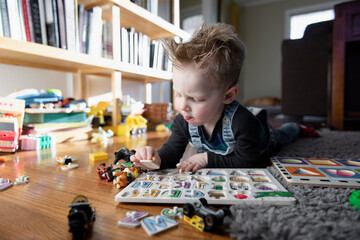 Young boy playing with alphabet puzzle on floor at home