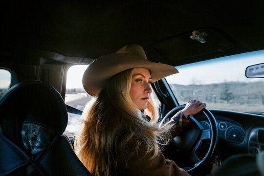Woman wearing cowboy hat driving truck