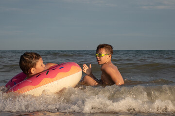 Two brothers 5 and 10 years old swim and have fun in the sea on a clear sunny day.