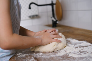 dough in flour kneading children's hands, one kid, child helps parents in kitchen, concept of a happy childhood, household help, homework, food preparation