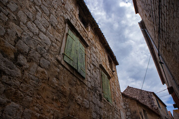 Fototapeta na wymiar Old, worn out, green coloured window shutters made from wood on the stone house, traditional in dalmatian region of Croatia