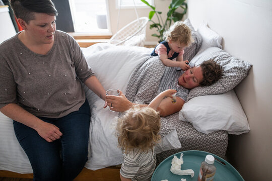 Family caring for sick mother resting in bed
