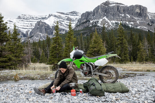 Man camping heating up canned food below Rocky Mountains, Canada