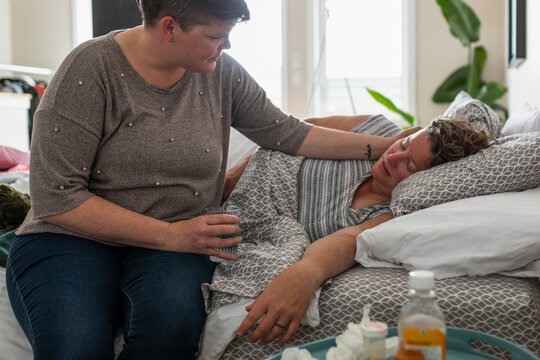 Affectionate lesbian woman caring for sick wife in bedroom