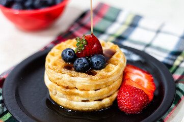 WAFFLES WITH STRAWBERRY BLUEBERRY AND SYRUP.