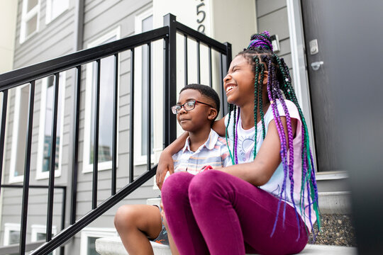 Happy affectionate brother and sister sitting on front stoop