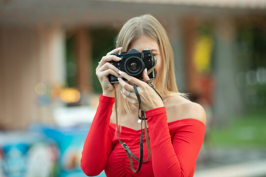 Young attractive stylish woman in park street style summer fashion trend holding vintage photo camera smiling happy emotion.
