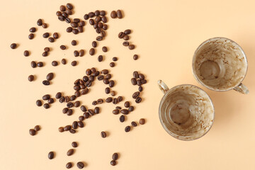 Scattered coffee beans on a light background with coffee mugs, top view-the concept of a pleasant...