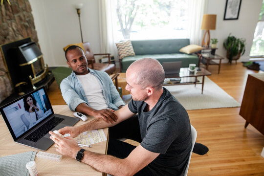 Gay Male Couple Video Conferencing With Doctor At Laptop