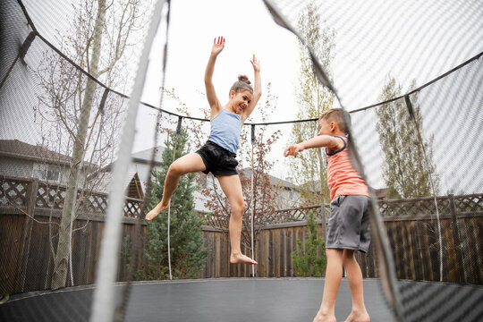 Girl and boy playing on trampoline