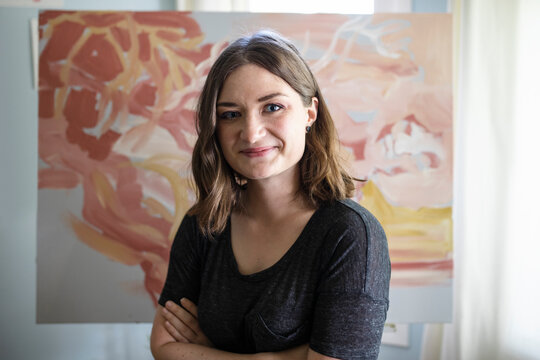 Portrait of artist in front of her painting