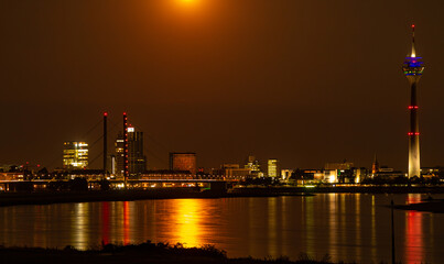 Düsseldorf und Rheinturm unter dem Vollmond in orangem Farbton