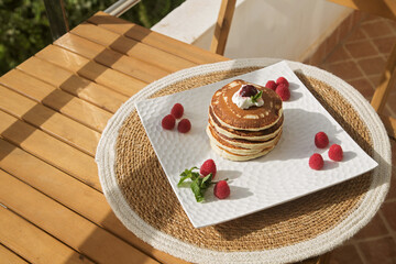 vanilla pancakes on a white plate with raspberries