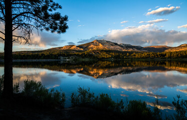 Sunset reflection of red rock cliff in calm lake.