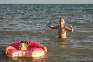 Two brothers 5 and 10 years old swim and have fun in the sea on a clear sunny day.