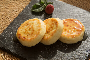 vanilla cheesecakes (cottage cheese pancakes) poured with honey on a black plate