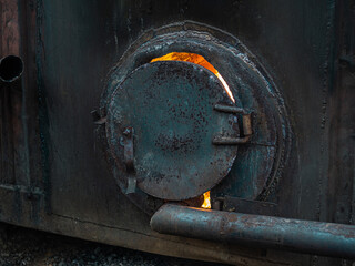Antique woods burning metal stove for the production of charcoal. Round metal door