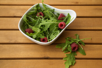white deep dish with fresh arugula and raspberries. The concept of healthy eating