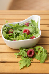 white deep dish with fresh arugula and raspberries. The concept of healthy food