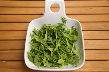 white deep plate with fresh arugula. The concept of healthy eating