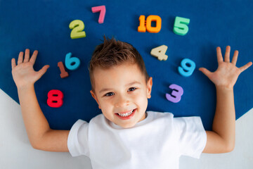 the boy is lying on the blue carpet around him numbers from 1 to 10