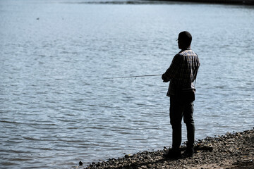 Fisherman holding spinning rod in hands and catching fish. Concept of sport, hobby and leisure time in the city.