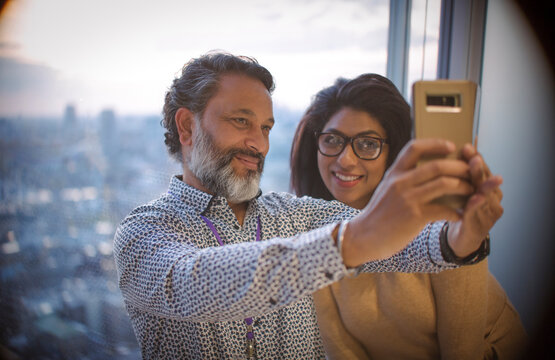 Business people taking selfie at highrise office window