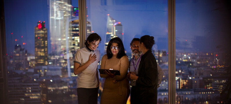 Business people with digital tablet working late at highrise window