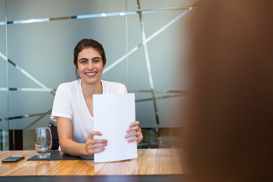 Portrait confident smiling businesswoman with paperwork in meeting
