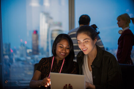 Smiling businesswomen with digital tablet working late in office
