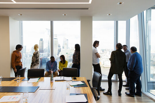 Business people talking at highrise conference room windows