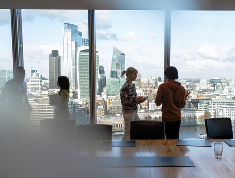 Business people talking at highrise office window, London, UK