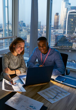 Business people working at laptop in highrise office, London, UK