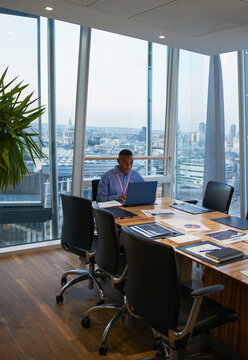 Businessman working at laptop in highrise conference room