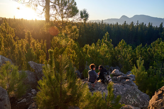 Young hiking couple relaxing on rock in sunny scenic woods - Powered by Adobe